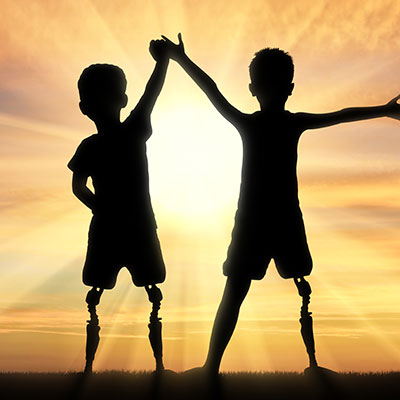 Two kids with prosthetic legs in the sunset
