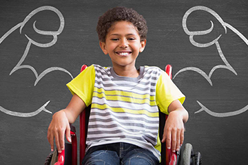 Boy in wheelchair in front of a chalkboard with muscles drawn on it