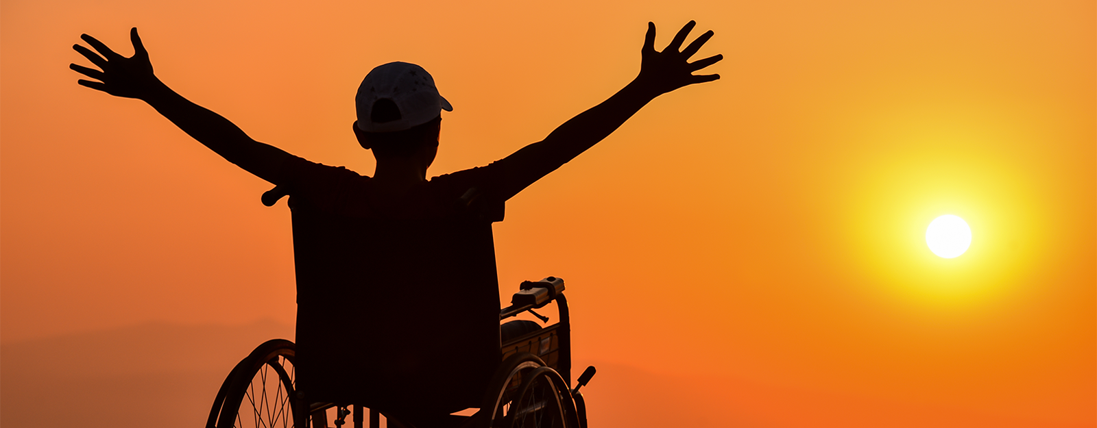 Boy in wheelchair in front of sunset